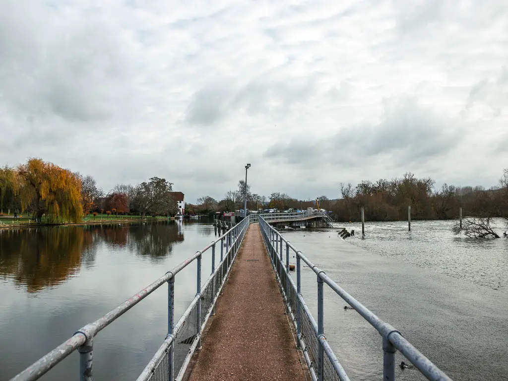 Looking along a long narrow bridge over the river thames, part way through the walk from Henley to Hambleden.