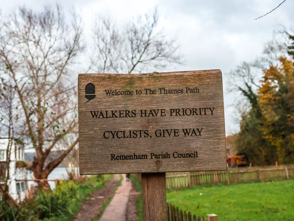 A wooden trail sign saying 'walkers have priority over cyclists' at the start of the walk from Henley to Hambleden.