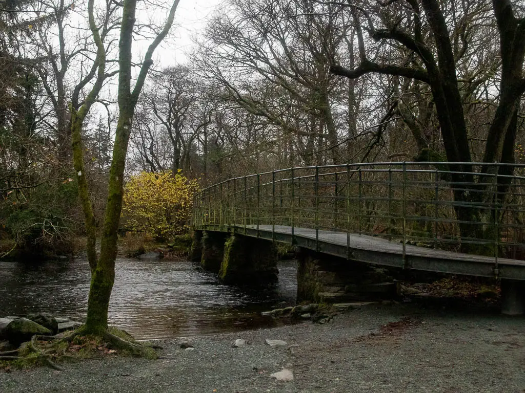 A bridge leading over the river into the woodland.