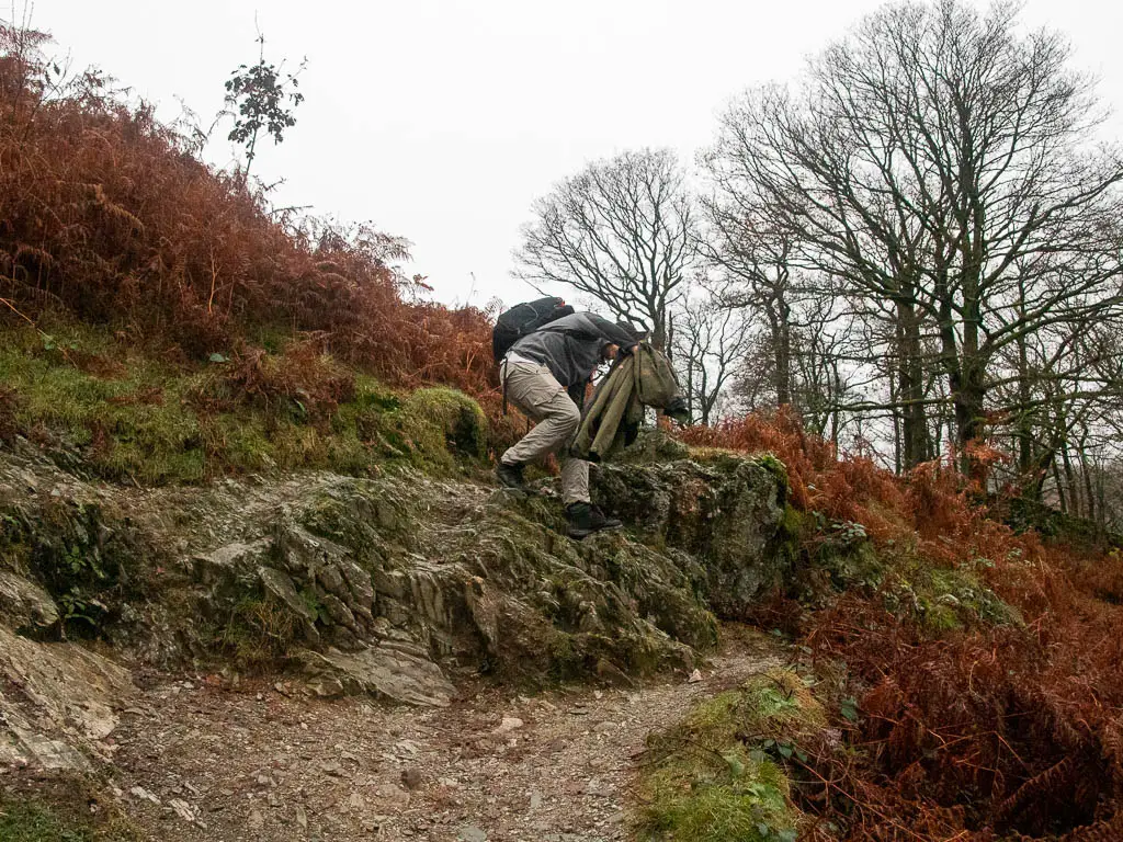 A man climbing down some rocks on the walk towards Rydal Cave.