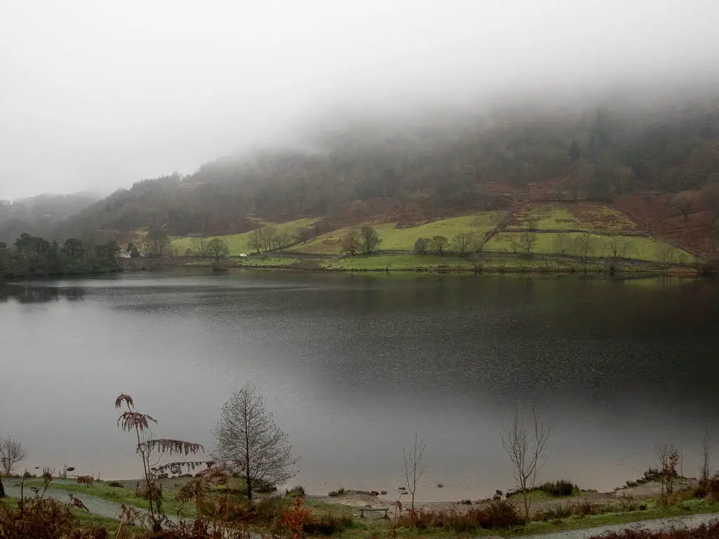 Looking across Rydal water with a green hill on the other side partially covered in fog on the walk back to the start.