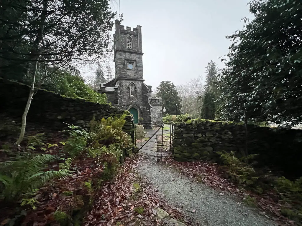 A stone wall with a metal gate, and a church on the other side.