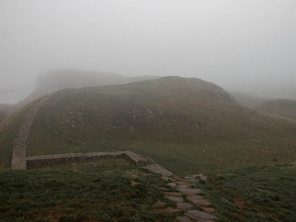 Looking down the hill towards a hill ahead, with fog everywhere.