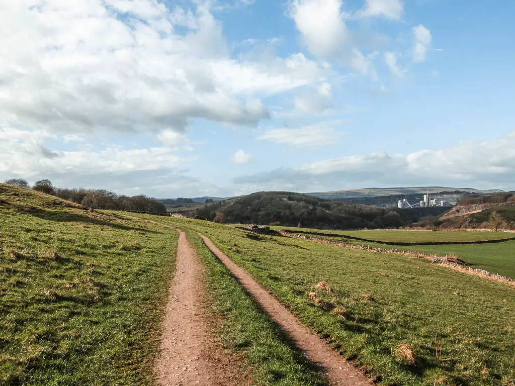 A track trail running across the side of a grass hill, near the end of the Chee Dale circular walk.