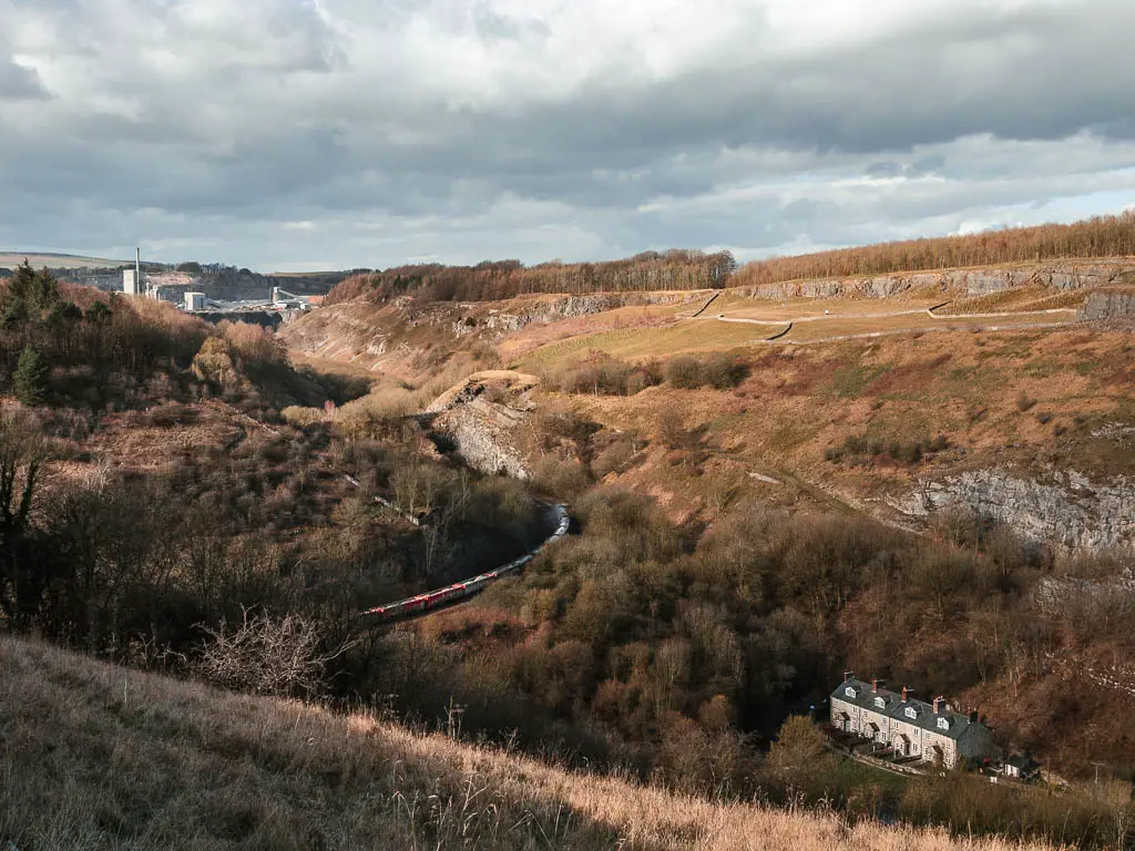 Looking down into the valley full of brown woodland, a small cottage and a train snaking through, at the parking spot for the start of the Chee Dale and stepping stones walk.