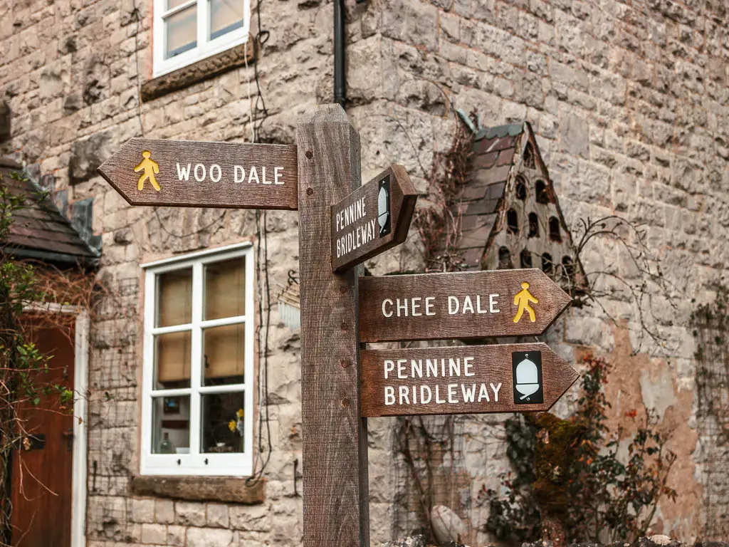 A wooden trail signpost in front of a stone house, which says Chee Dale, at the start of the walk.