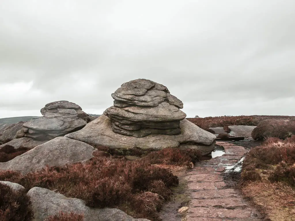 Two rock tors next to the stone paved path on the walk along Derwent Edge.