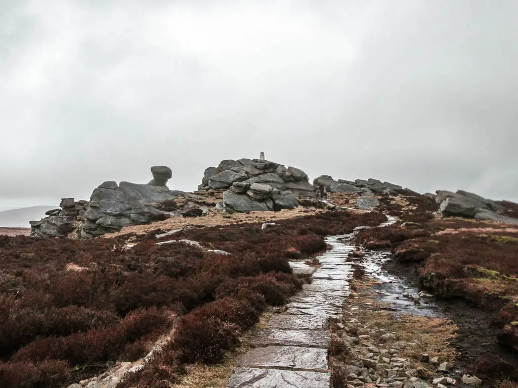 A stone paved trail leading towards Back Tor at the end of the walk along Derwent Edge. There is a white trig point on top of Back Tor.