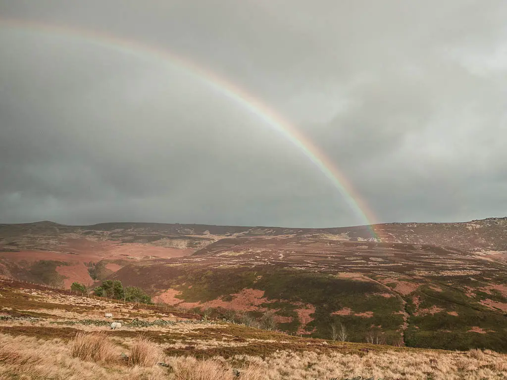 A rainbow rising above Derwent Edge halfway through the walk. It's a cloudy misty day.