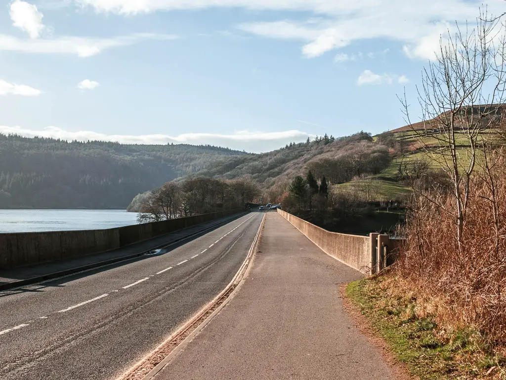 A road over the viaduct, with woodland trees and hills on the other end.