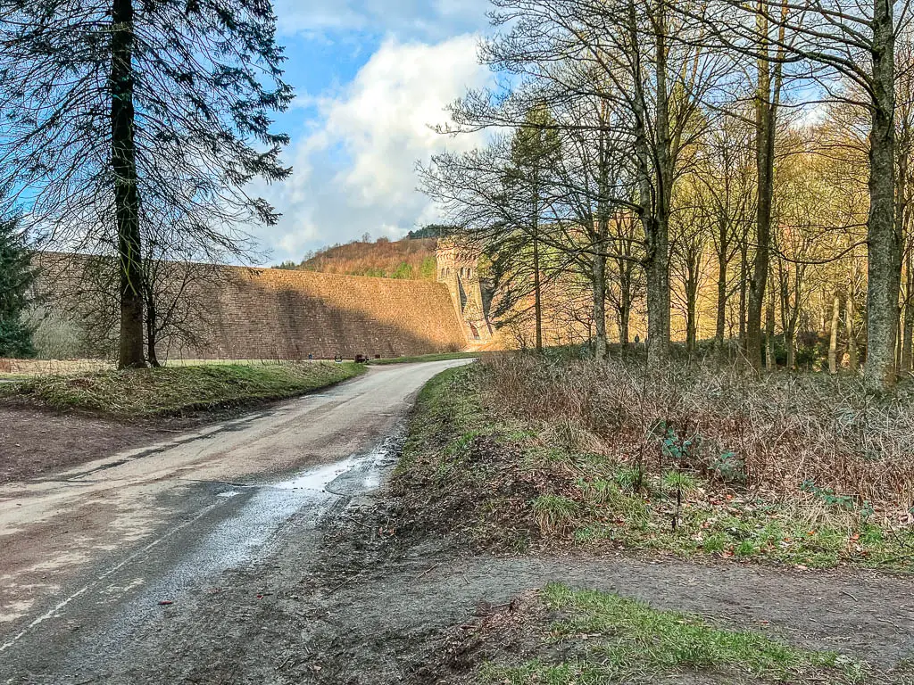 A road on the left leading towards the Derwent Dam, and a dirt trail leading to the right.