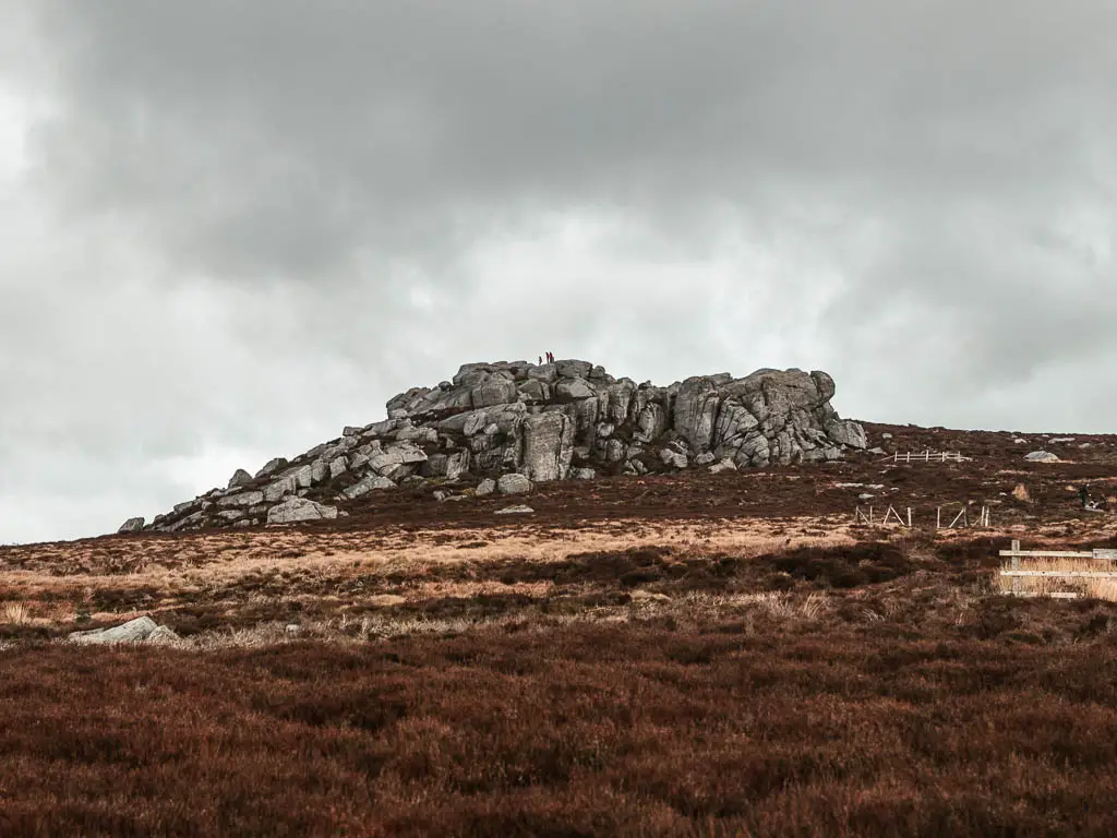 The large rocky outcrop of Simon's Seat with people walking on the top of it, in the Yorkshire Dales.