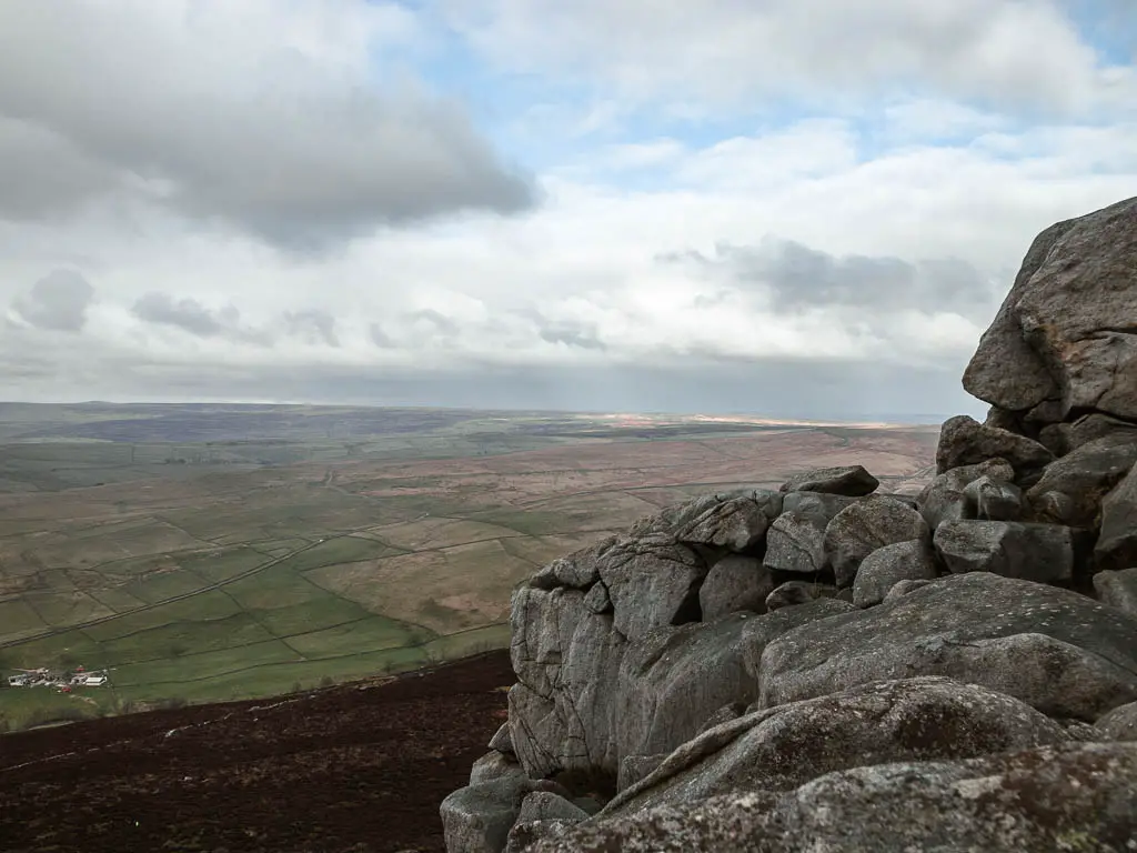 A large rock face to the right, with a view down to the vast landscape to the left.
