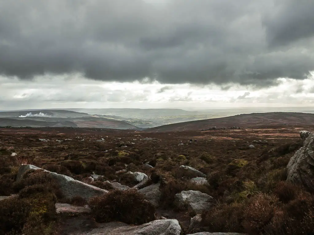 Looking across the moor, to a view into the valley way in the distance, when walking around Simon's Seat.