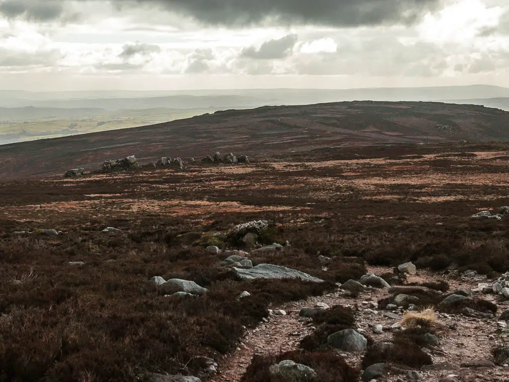 Looking across the vast moorland, with a view to some rocky outcrops ahead, on the walk away from Simon's Seat towards the Valley of Desolation.