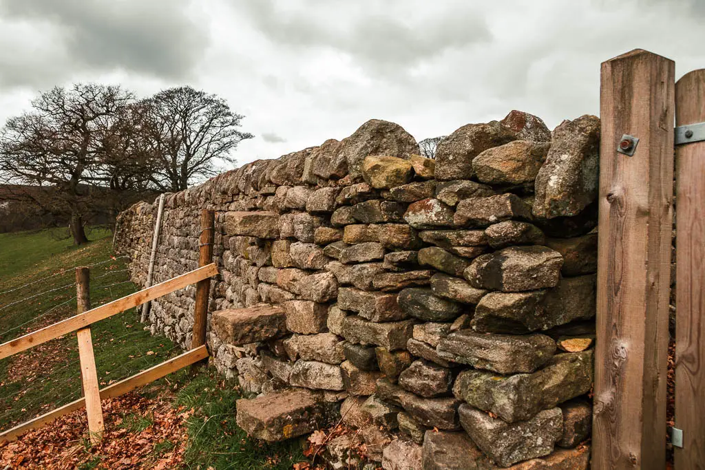 A stone wall with stone steps leading over it.