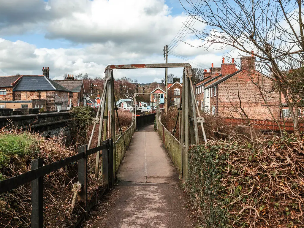 The path leading over a bridge, and the village houses on the other side.