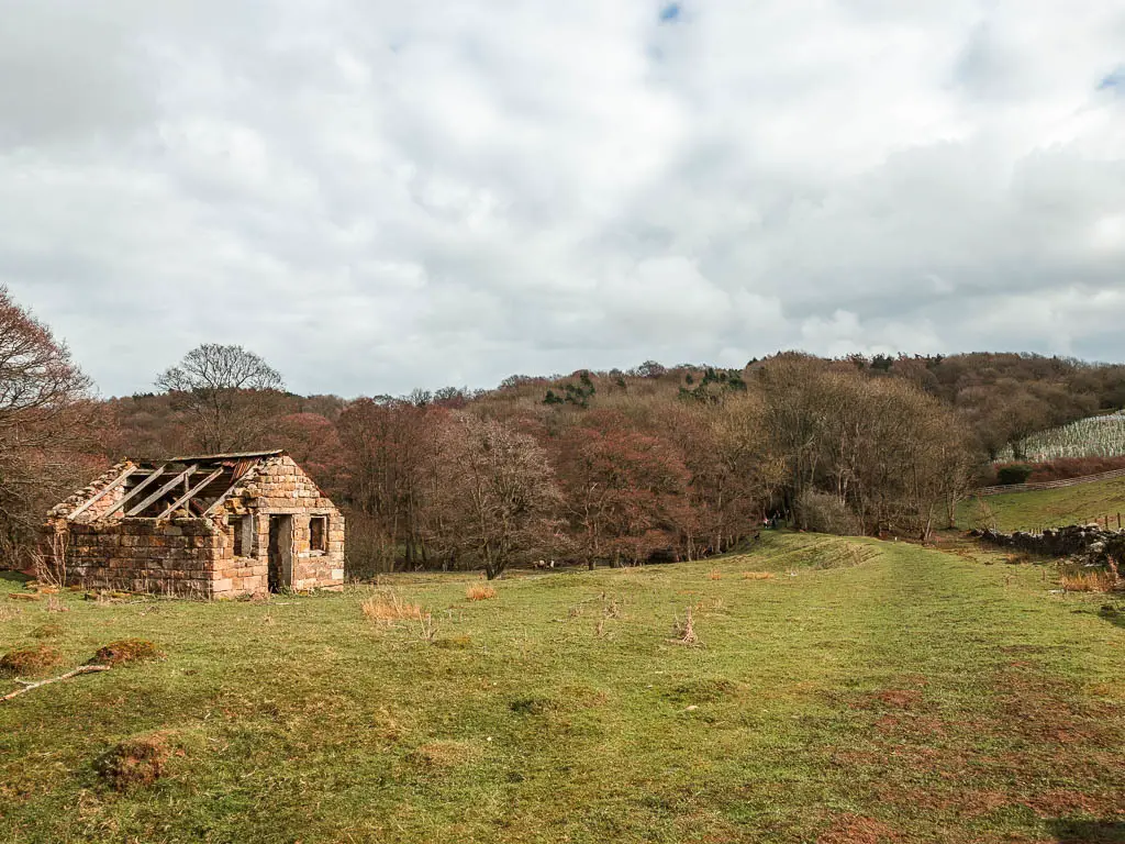 A large grass field, with a ridgeway along the right side, and a falling down brick shed on the left, on the walk back to Goathland from Grosmont.