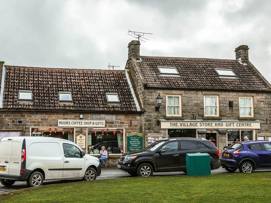 Two village shops in Goathland, with cars parked in front of them.