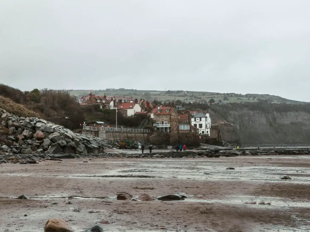 Looking across the sand towards the coastal village of Robin Hood's Bay, on a grey day.