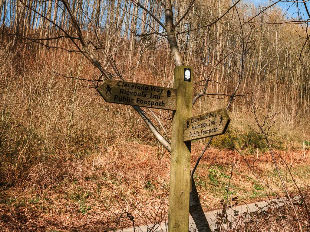 A wooden trial signpost pointing the way to walk to Rievaulx Abbey and the Cleveland Way to the left, and Helmsley back.