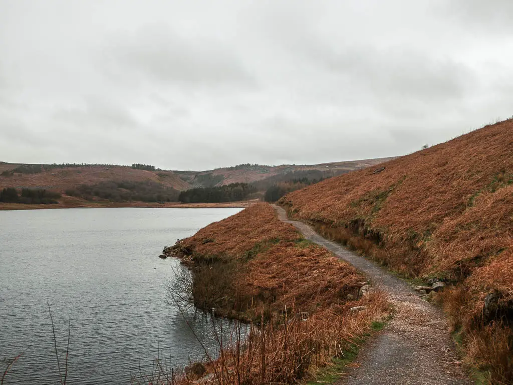 A narrow path cutting across the side of the hill, with the Grimwith Reservoir at the bottom on the left, part way though the walk.