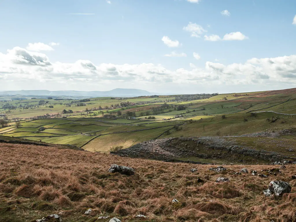 Looking down the hill to the rocky top of Malham Cove, and the hills and fields in the distance.