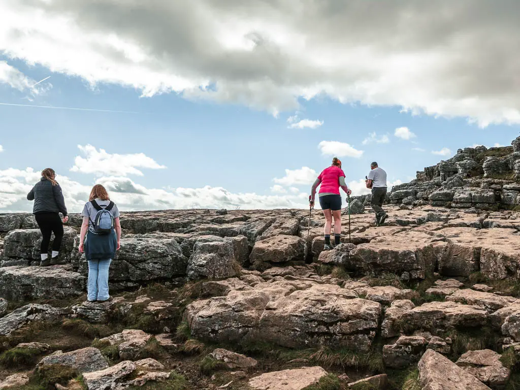 People walking along the rocks with gaps at Malham Cove.