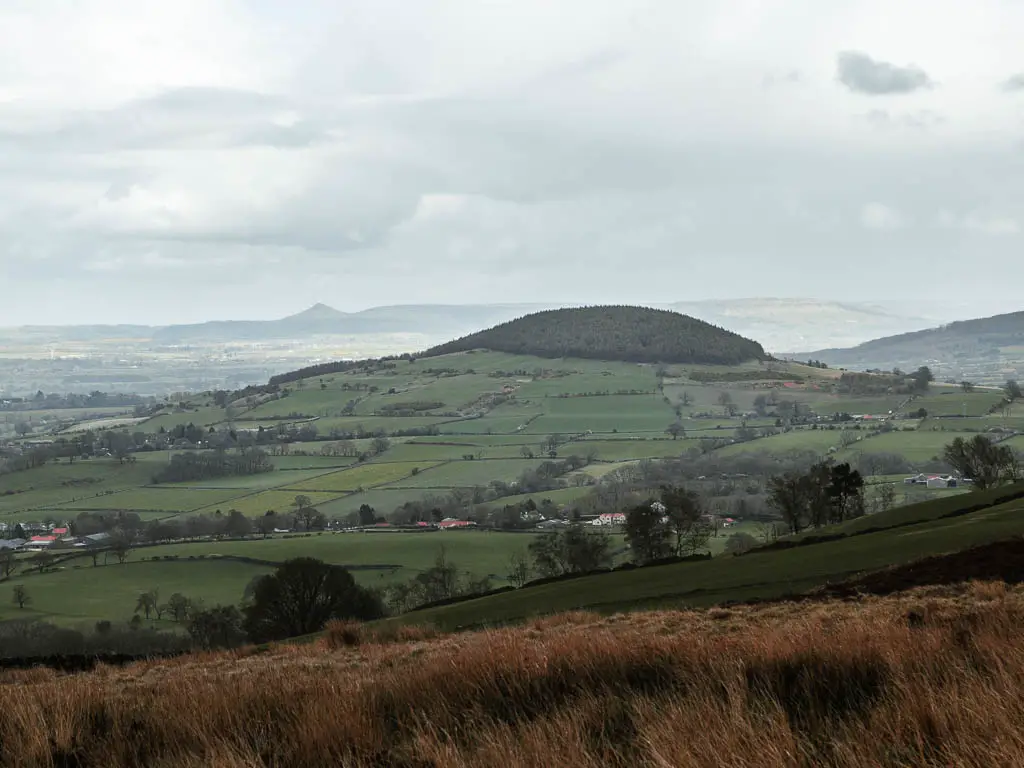 Looking across the vast green landscape with hills in the distance on the walk from Osmotherley on a misty day.