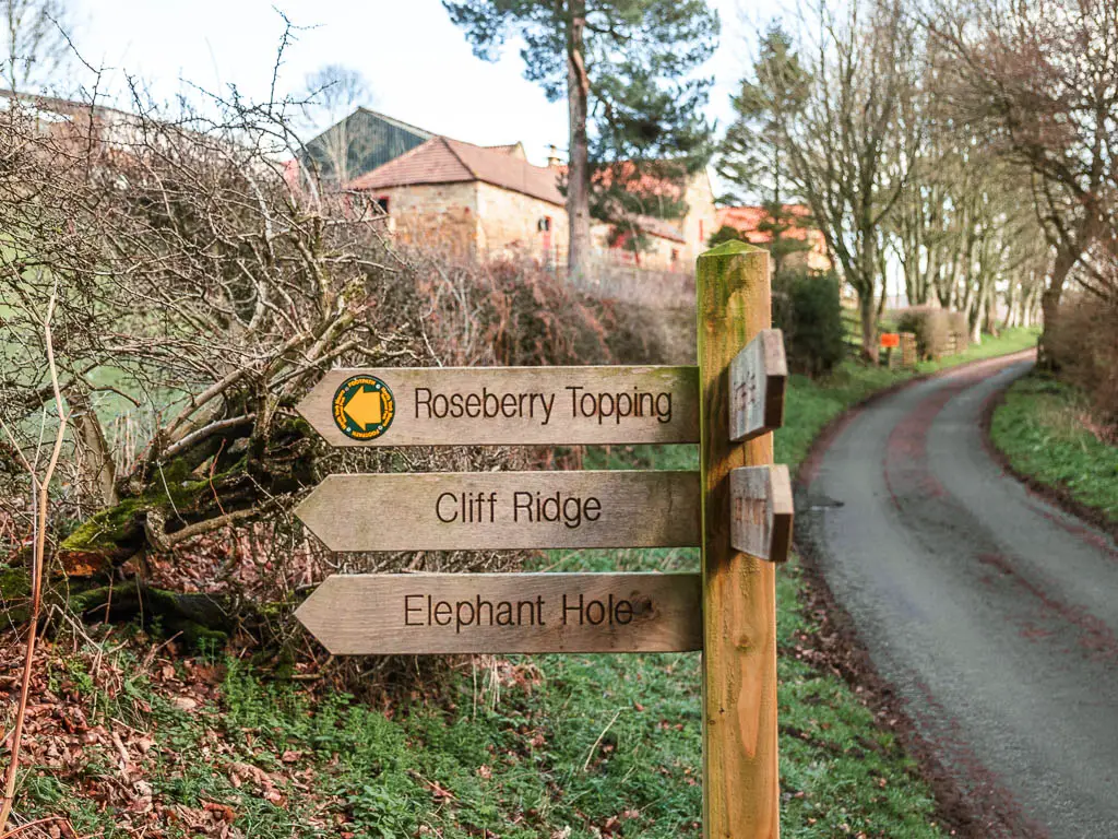 A wooden trail signpost pointing left to walk to Roseberry Topping.