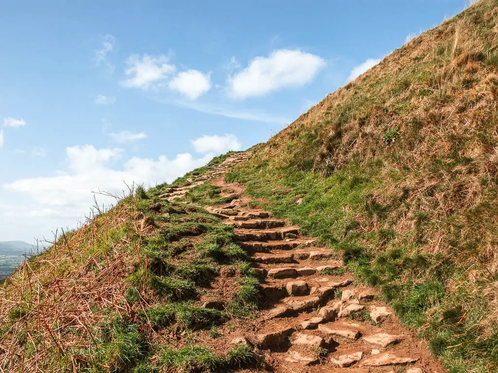 Rugged stone steps leading up the side of the grass hill.
