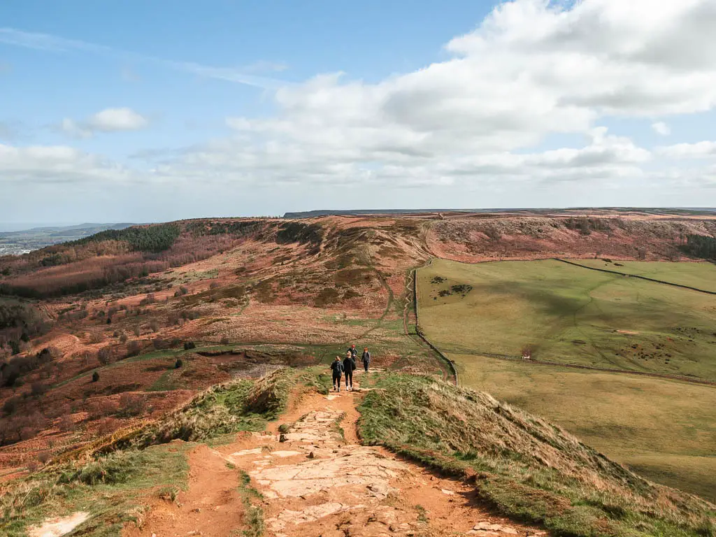 Looking down to the valley, and a ridge ahead on the walk down off Roseberry Topping. there are a few people walking down the hill.