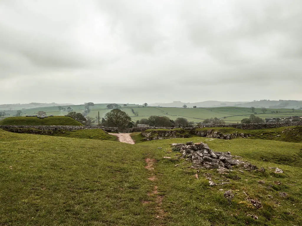 An undulating grass field, with the trail leading straight ahead. 