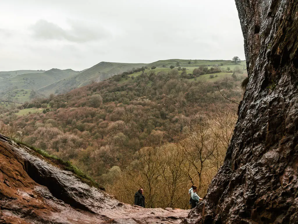 Standing in Thor's Cave, looking out to the view down across the Manifold Valley. there are two people standing outside the cave.