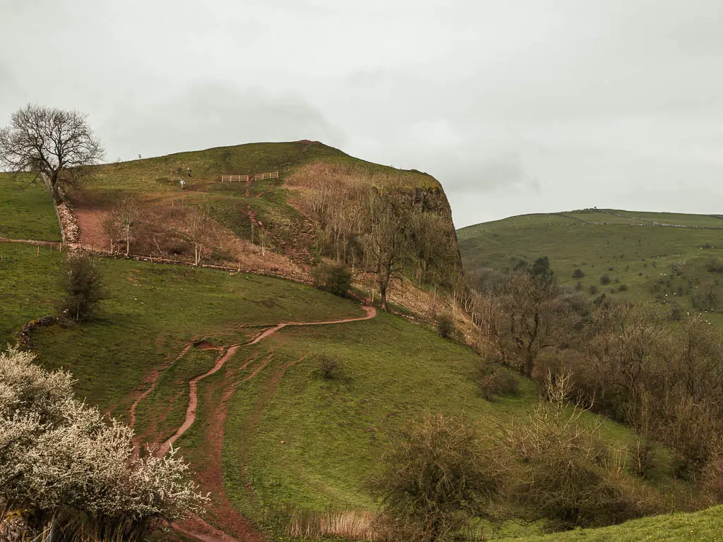 Looking down towards the straggly dirt trail running across the field, towards the big cliff where Thor's Cave is.