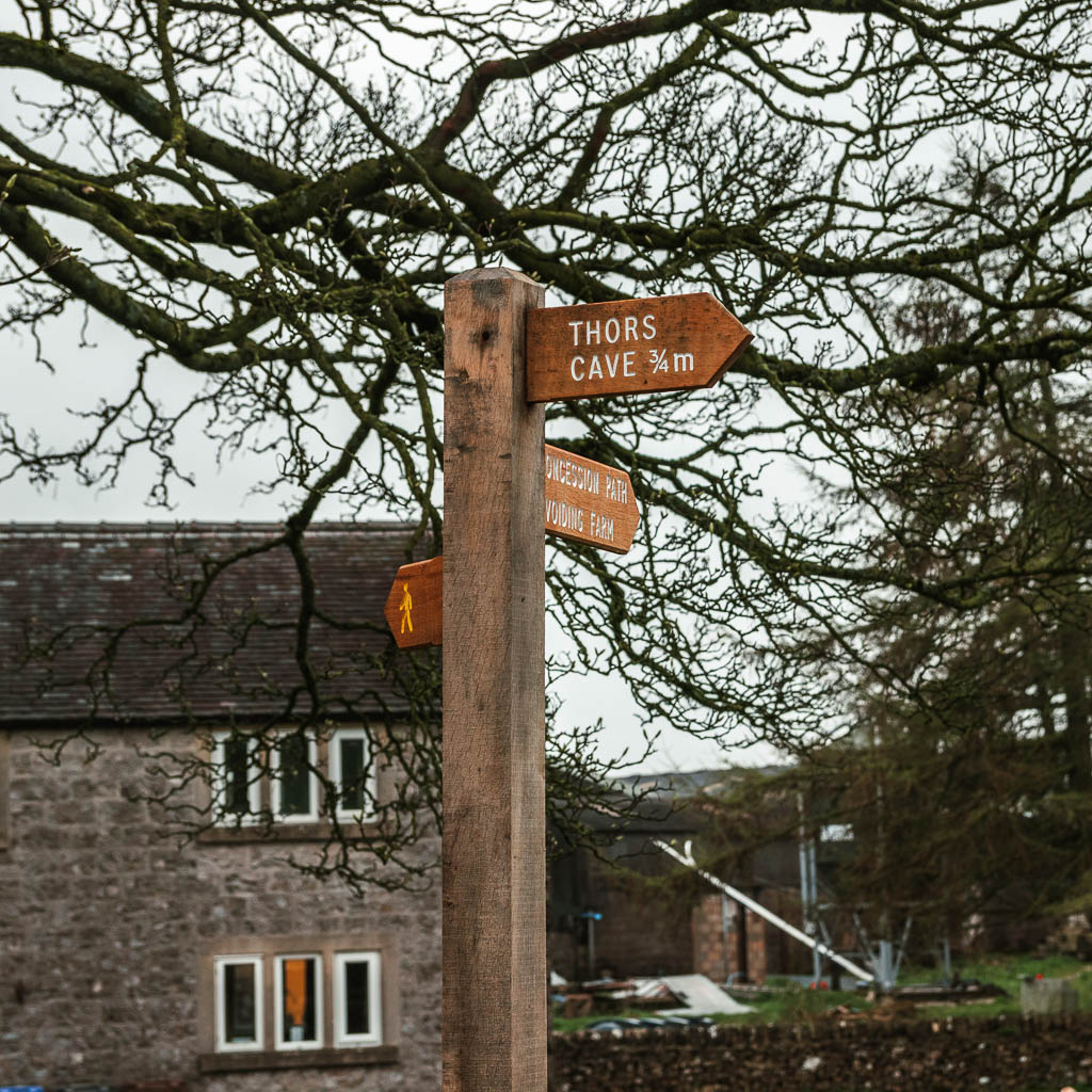 A wooden trail signpost pointing the way to walk to Thor's Cave.