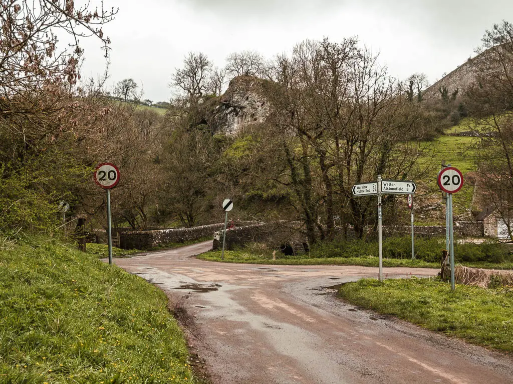 A road junction, with two 20 miles per hours signs, and a stone bridge straight head.