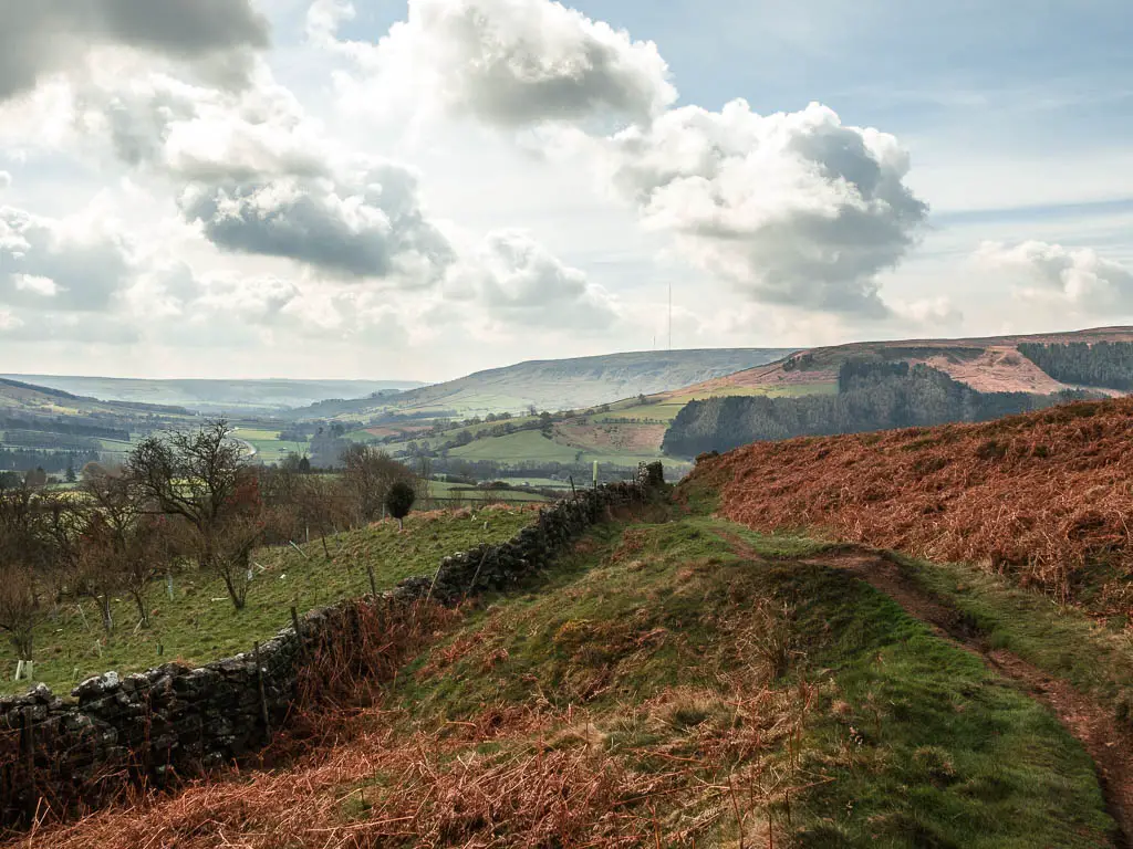 Looking down along the underling hill, with a stone wall cutting across it and the valley and hills in the distance.