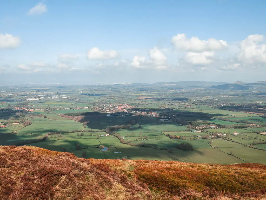 Looking down towards a mass of green fields as far as the eye can see.