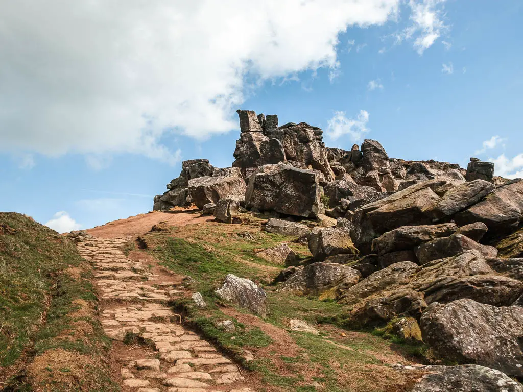 A paved stone trail leading up to the left, with the mass of rocks of the Wainstones on the right on the walk up to them. 