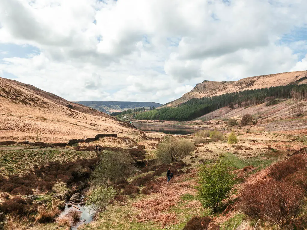 Looking across the rugged grassy moorland through the valley with hills rising up on either side.