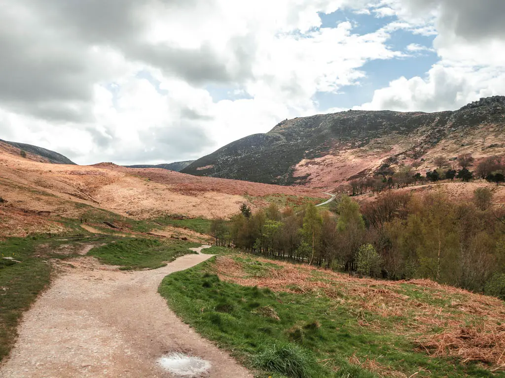 A path on the left and grass on the right with undulating hills ahead.
