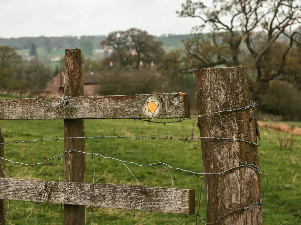 A yellow arrow on a wooden fence, pointing to the left, partway through the circular walk towards Druid's Temple. 