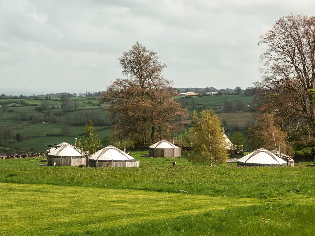 A field with white yurts at Swinton Bivouac, at the start of the Druid's Temple circular walk.