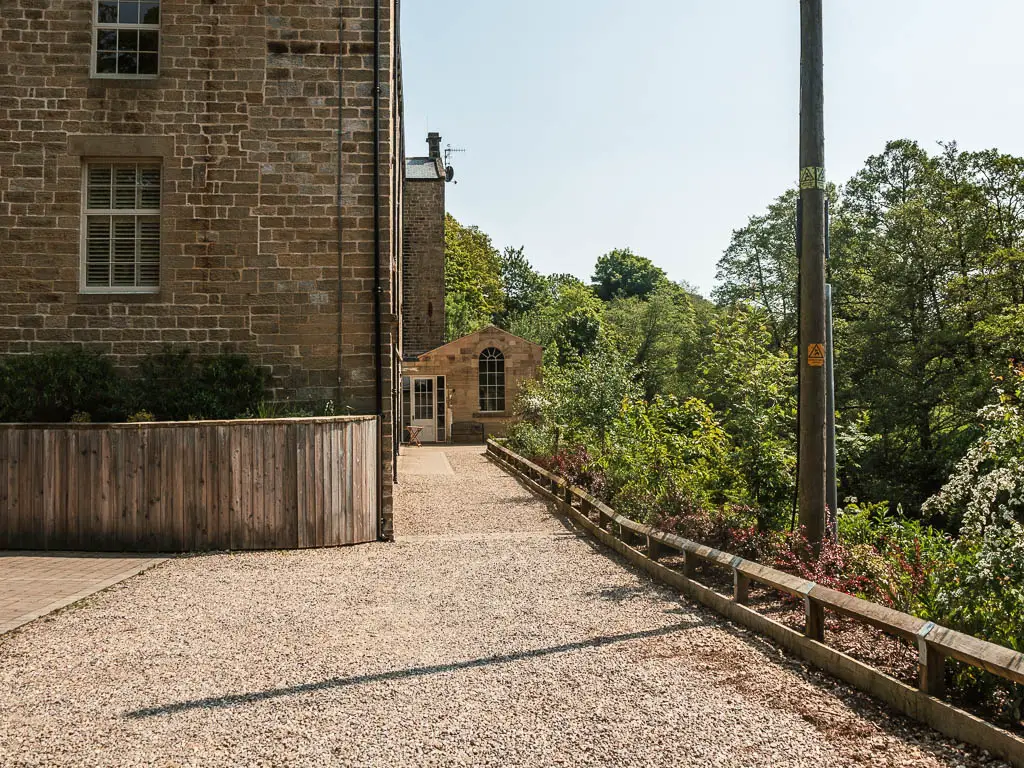 A gravel driveway, with a brick house on the left, and a small conservatory straight ahead. 