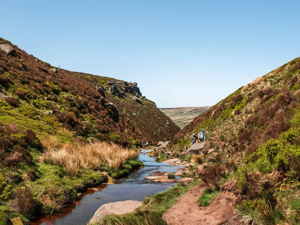 Looking down along the calm river through the narrow valley, with a dirt trail on the right, on the walk up to the Trinnacle.