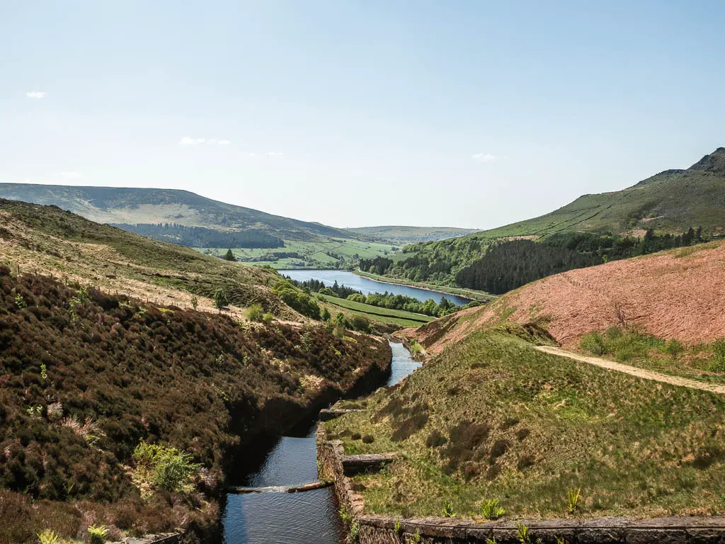 Looking down along the water flowing through a dip in the hills, towards the reservoir below.