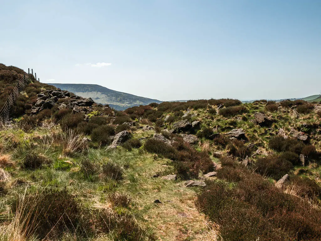 The ground covered in wild grass, heather and rocks.