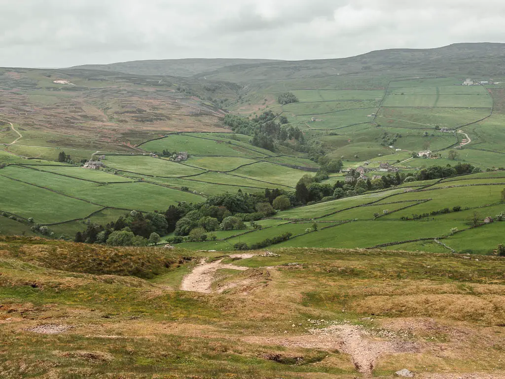 Looking down the hill to the valley of green grass fields below, on the Fremington Edge circular walk.