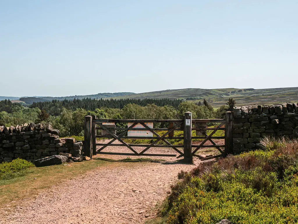 A wide path leading to a wooden gate in the stone wall.